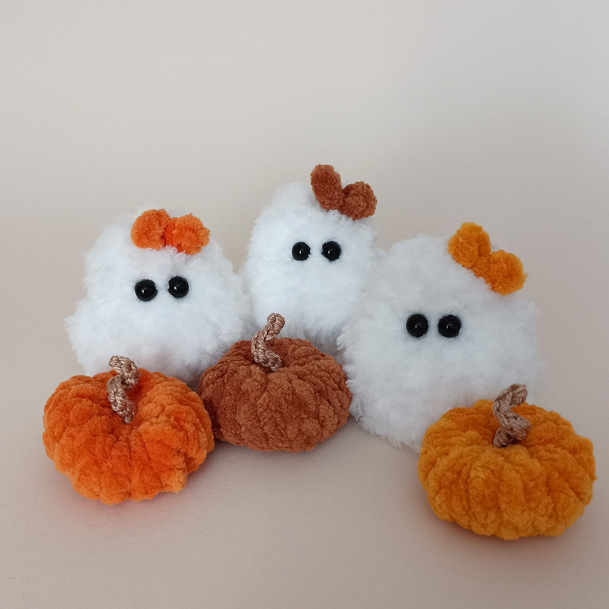 Trio of tiny handmade white crochet ghosts with colorful bows and mini plush pumpkins, cozy autumn and Halloween desk pets collection, perfect cute gift for coworkers by PlushWhisper.