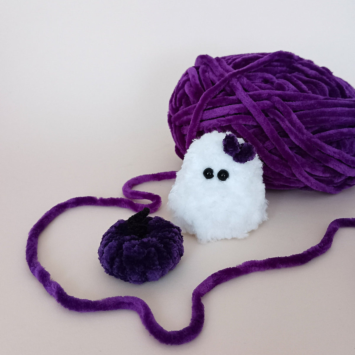 White handmade ghost with a purple bow and matching purple pumpkin, a tiny Halloween decor set made from soft yarn