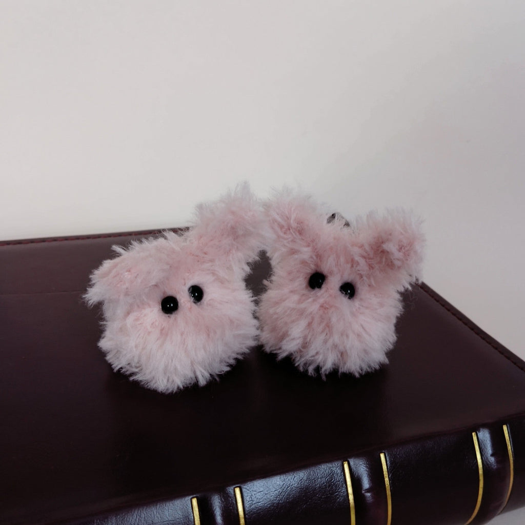 Two tiny pink fluffy handmade bunny desk friends sitting on a dark brown book