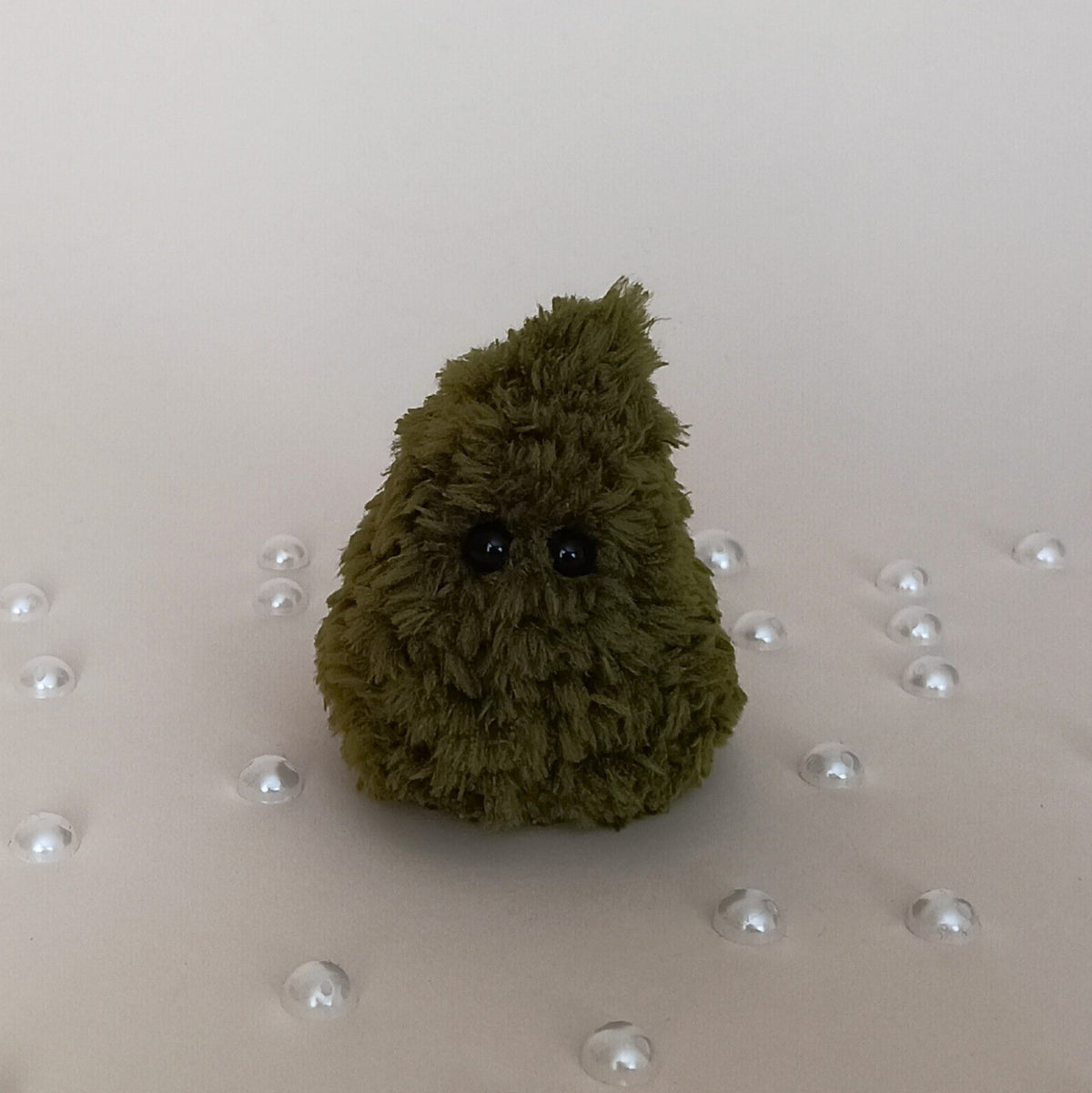 Tiny green crochet Christmas tree without decorations, handmade fluffy miniature holiday decor surrounded by pearl accents