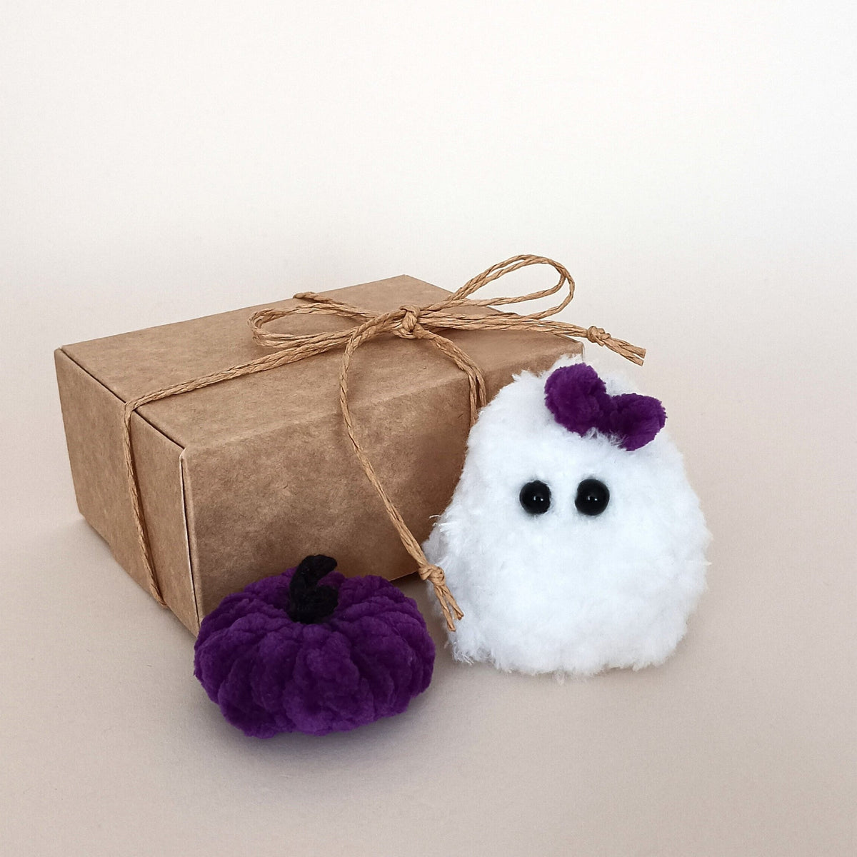 White handmade ghost with a purple bow and matching purple pumpkin displayed beside a kraft gift box, a cozy Halloween decor gift set
