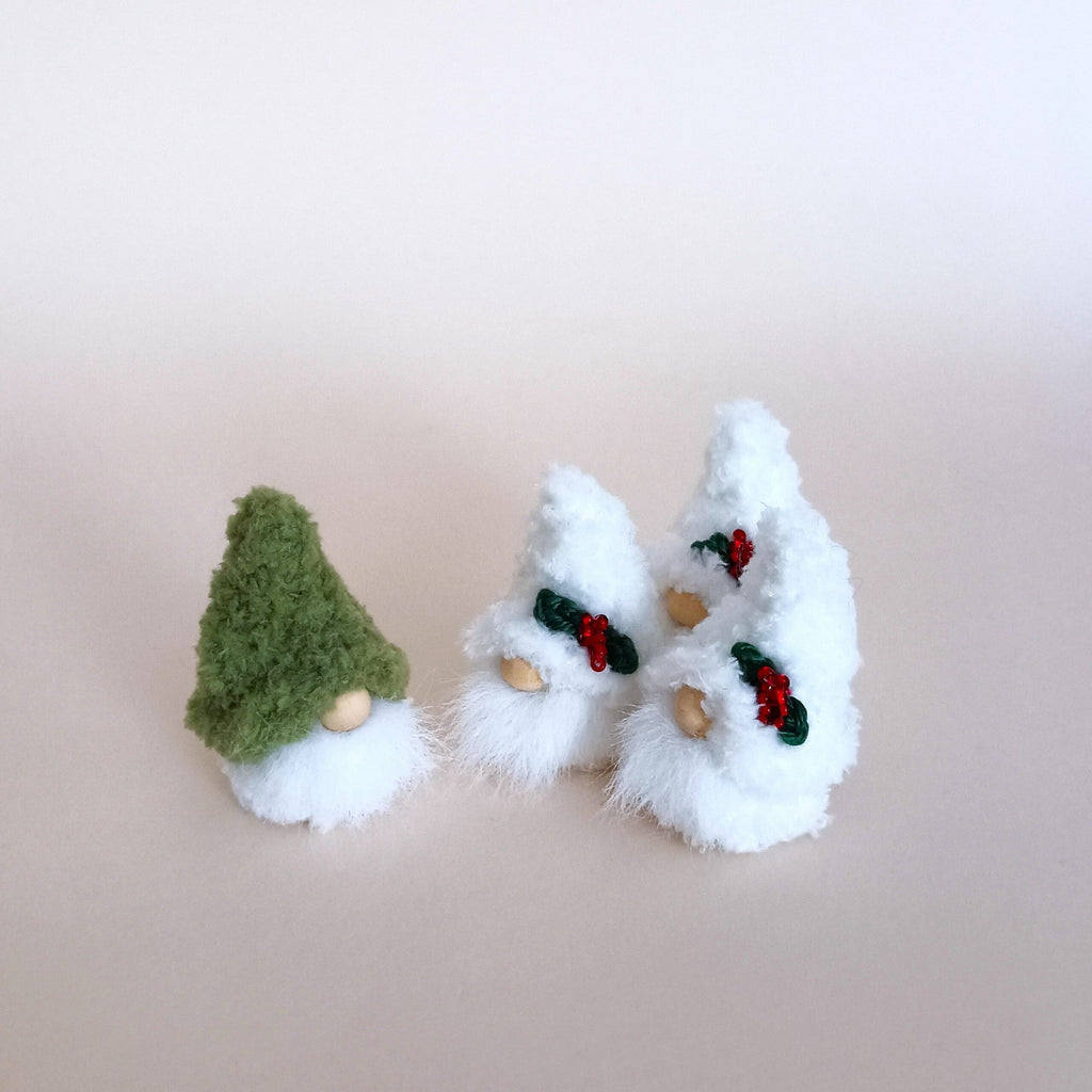 A set of miniature holiday gnomes including a small green winter forest gnome and a group of tiny white Christmas plush gnomes for tiered tray decor.