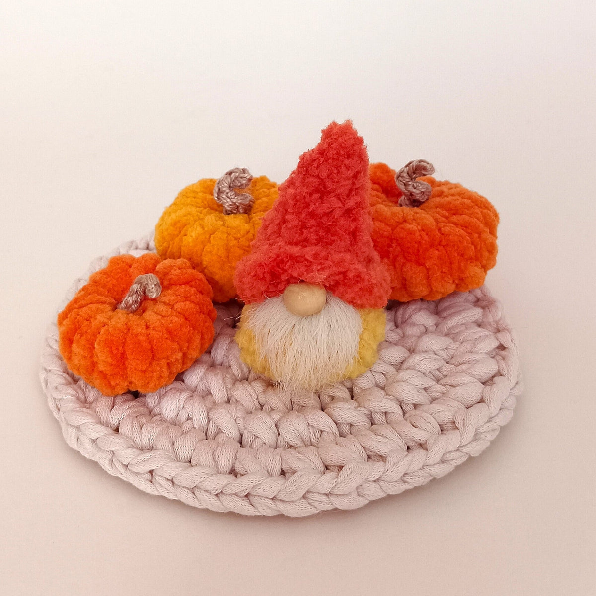 Single pumpkin spice gnome style option sitting with miniature crocheted plush pumpkins on a round macrame mat. Tiny fall tiered tray decor object and unique autumn themed housewarming gift package for adults.