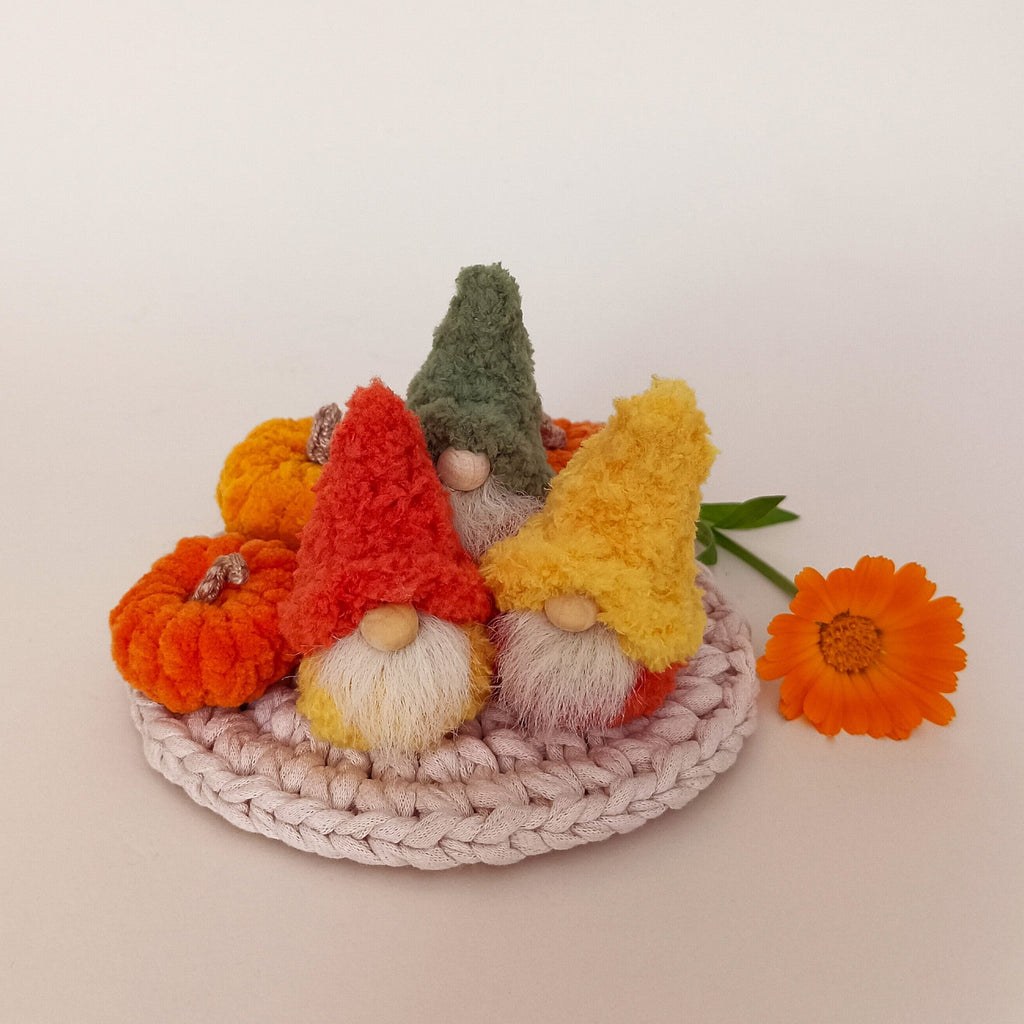 A full harvest set variation featuring three tiny handmade autumn gnomes and miniature crocheted plush pumpkins on a round woven mat. Cozy Thanksgiving tiered tray decor and a unique pumpkin spice themed housewarming gift package for adults.