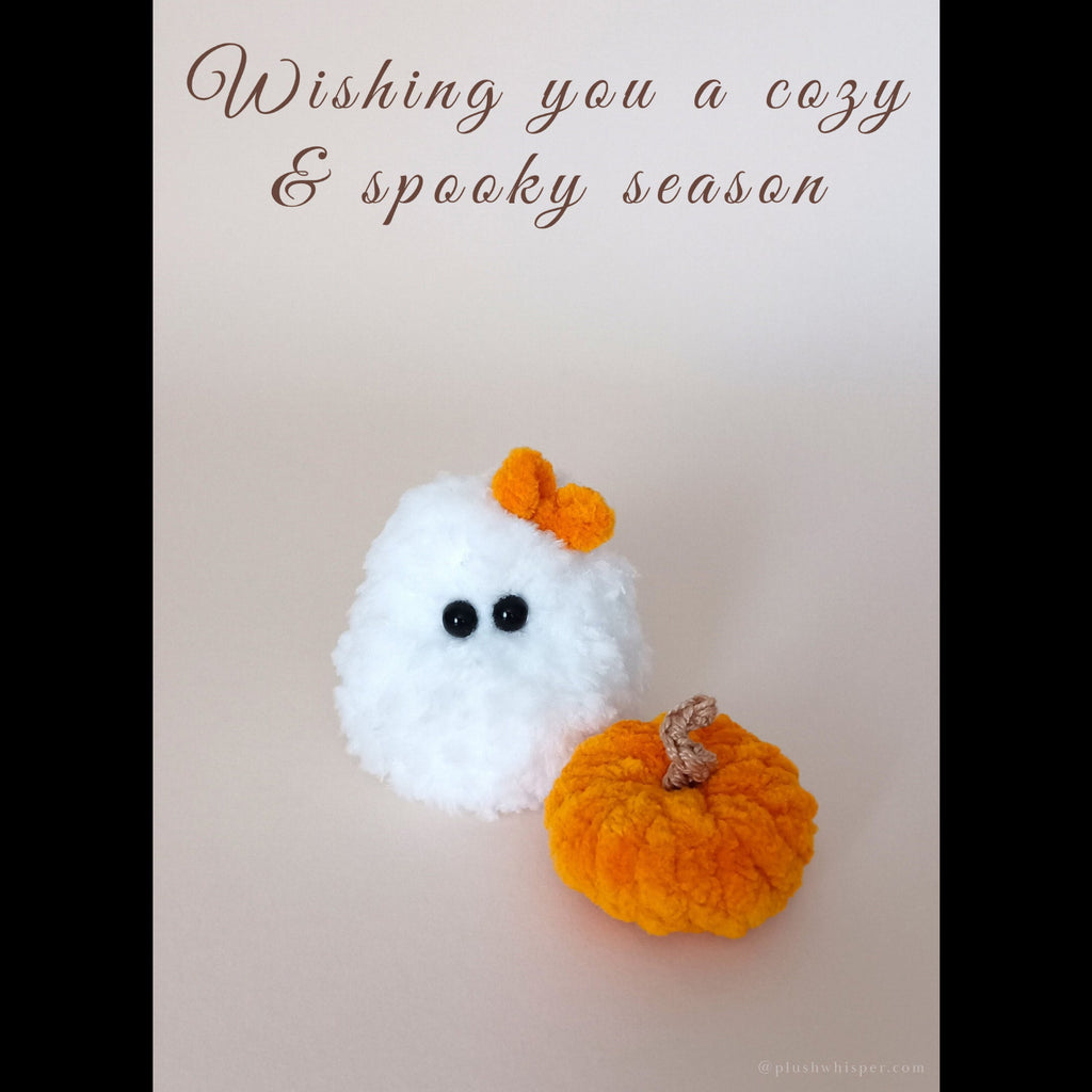 A high-end 5x7 printable Halloween decor card showing a fluffy white miniature phantom crocheted by hand from plush textured yarn with a small decorative pumpkin. Elegant minimalist typography reads Wishing you a cozy & spooky season at the upper part. Ideal for sophisticated spooky aesthetic home office spaces.
